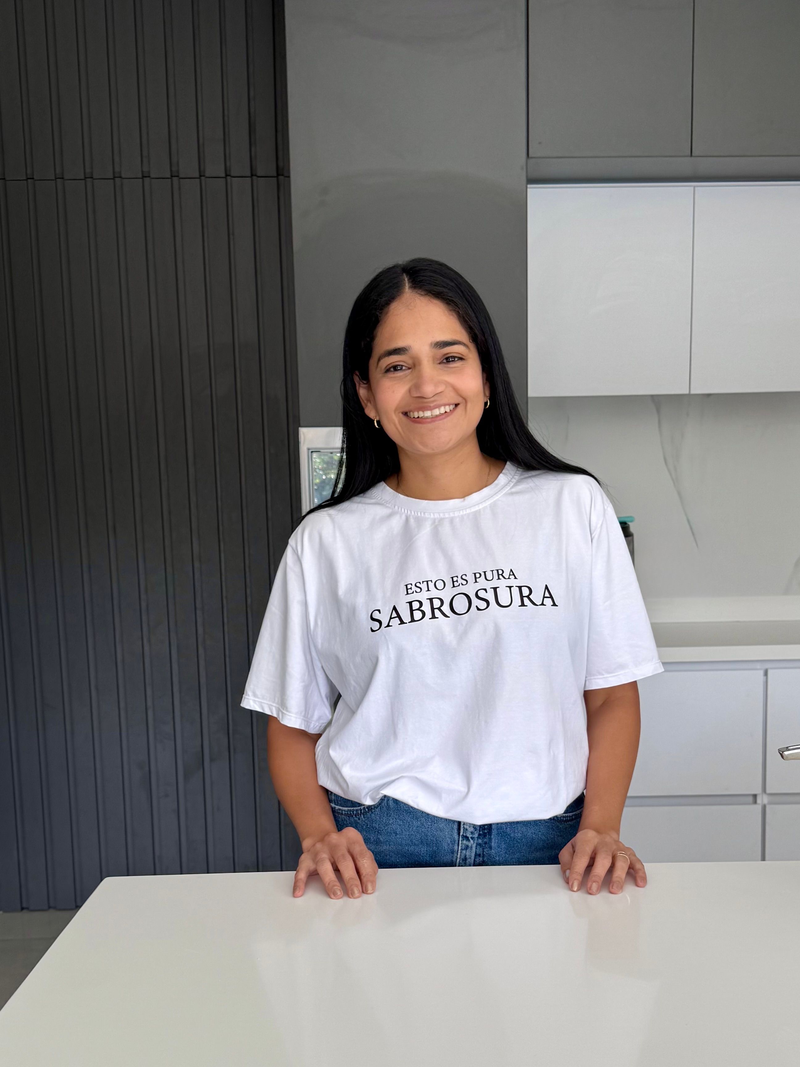 Dra. Rochy en su cocina, con camiseta de la marca Pura Sabrosura